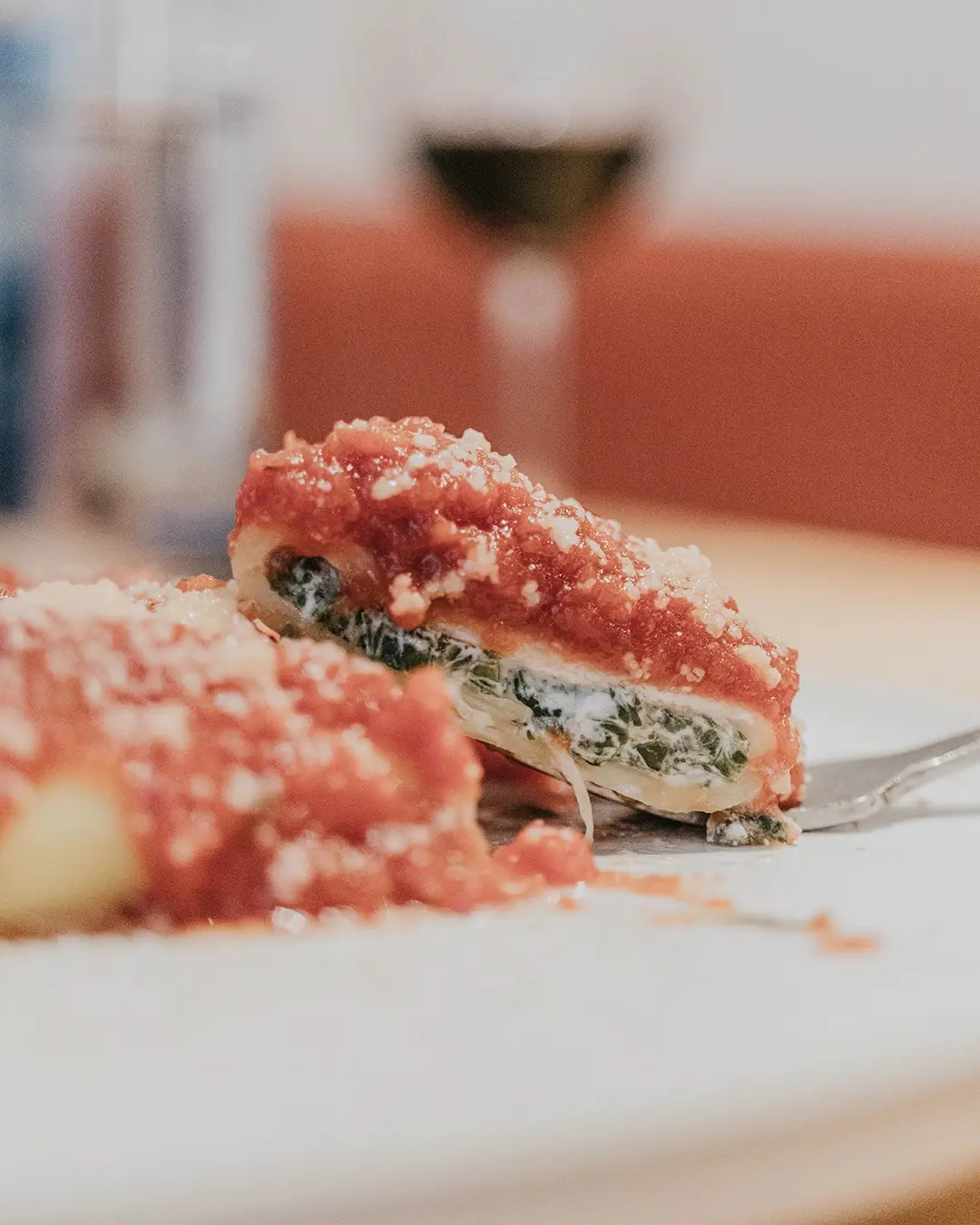 Canelón de queso fresco y espinacas con tomate y queso rallado