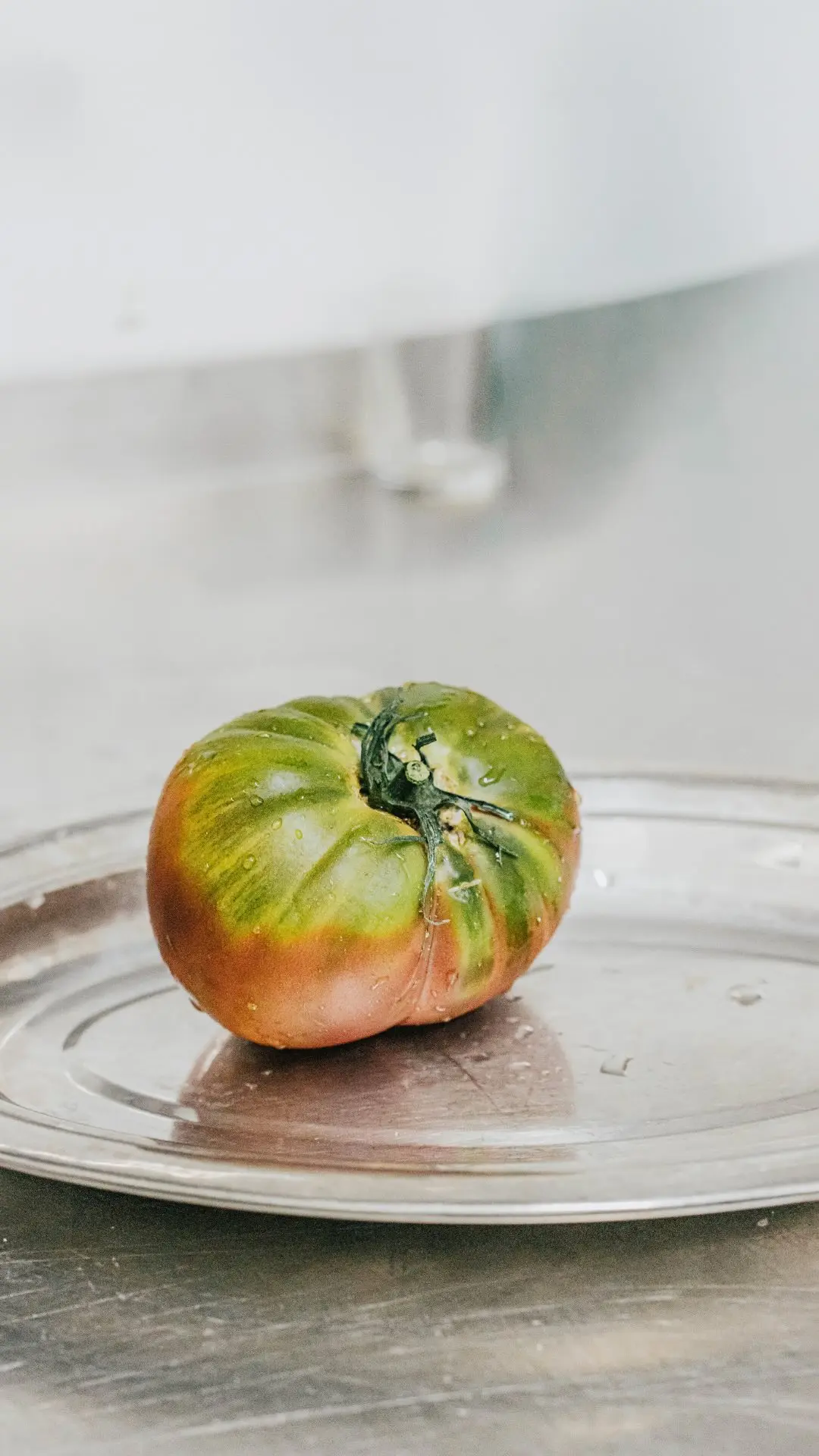 Tomate de temporada sobre la mesa de acero de la cocina