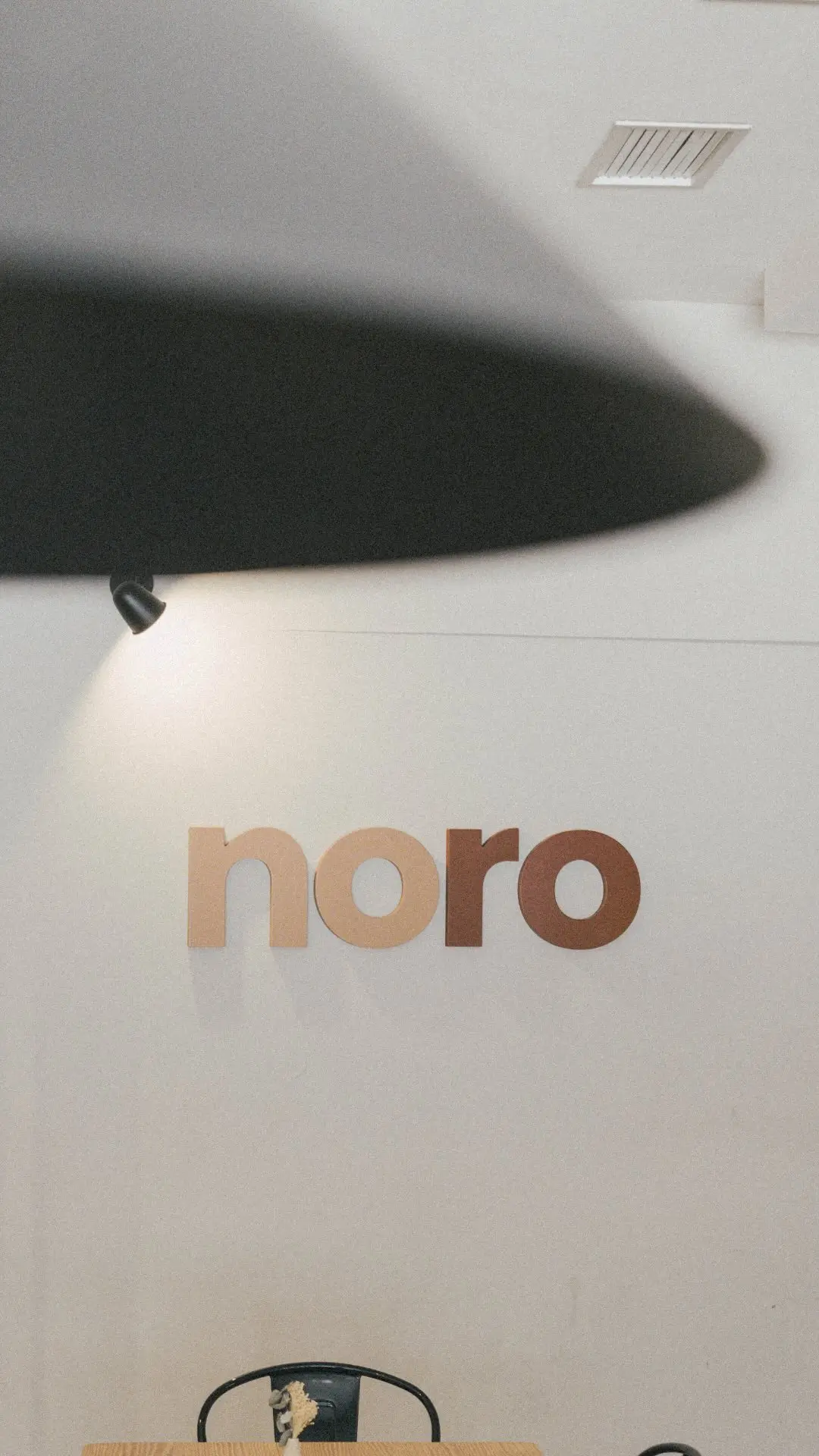 Rincón de la sala con el logotipo de Noro y una lámpara